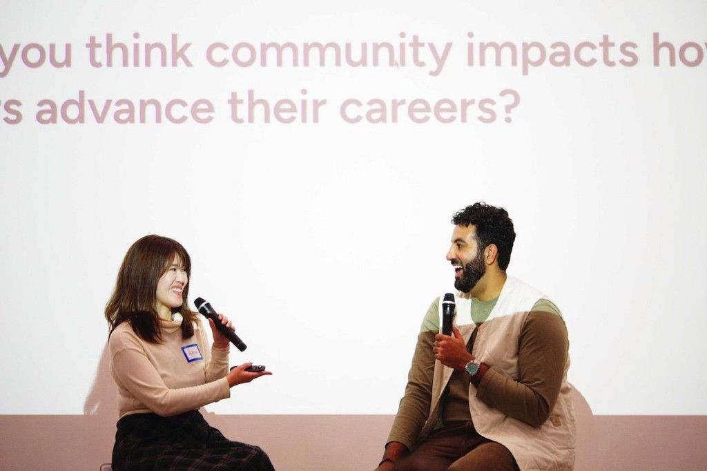 Woman and man on stage at a community event, both holding microphones, laughing during a panel discussion